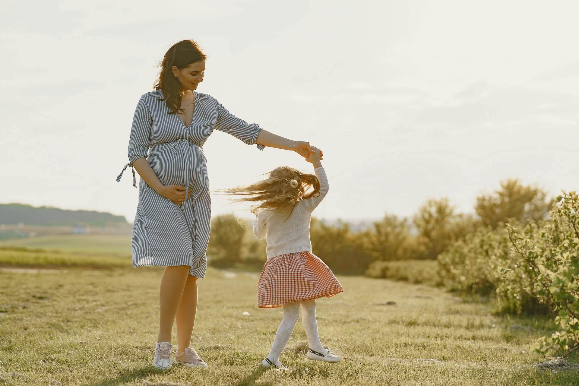 Těhotná maminka s malou dcerou na louce. Jak si udržet intimní komfort během horkého léta v těhotenství