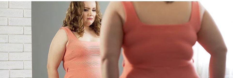Žena stojí před zrcadlem